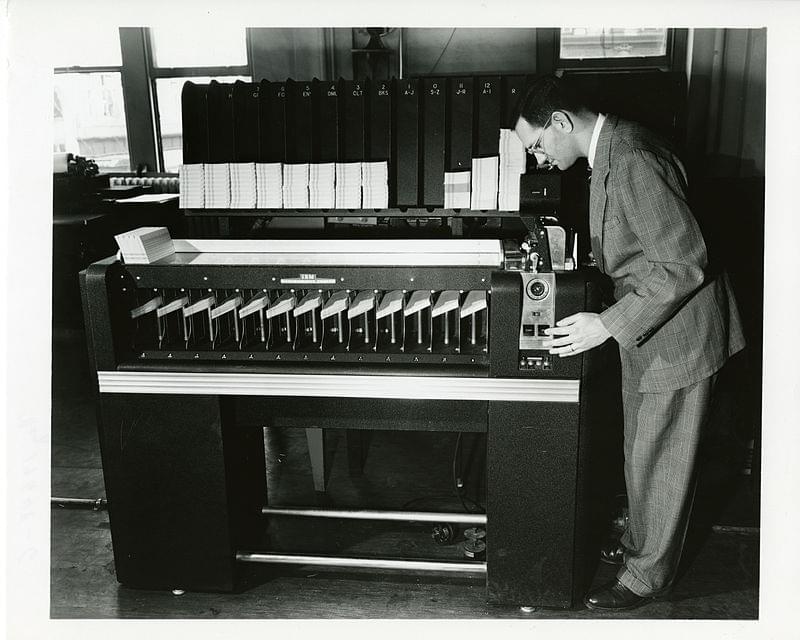 man standing over old computer
